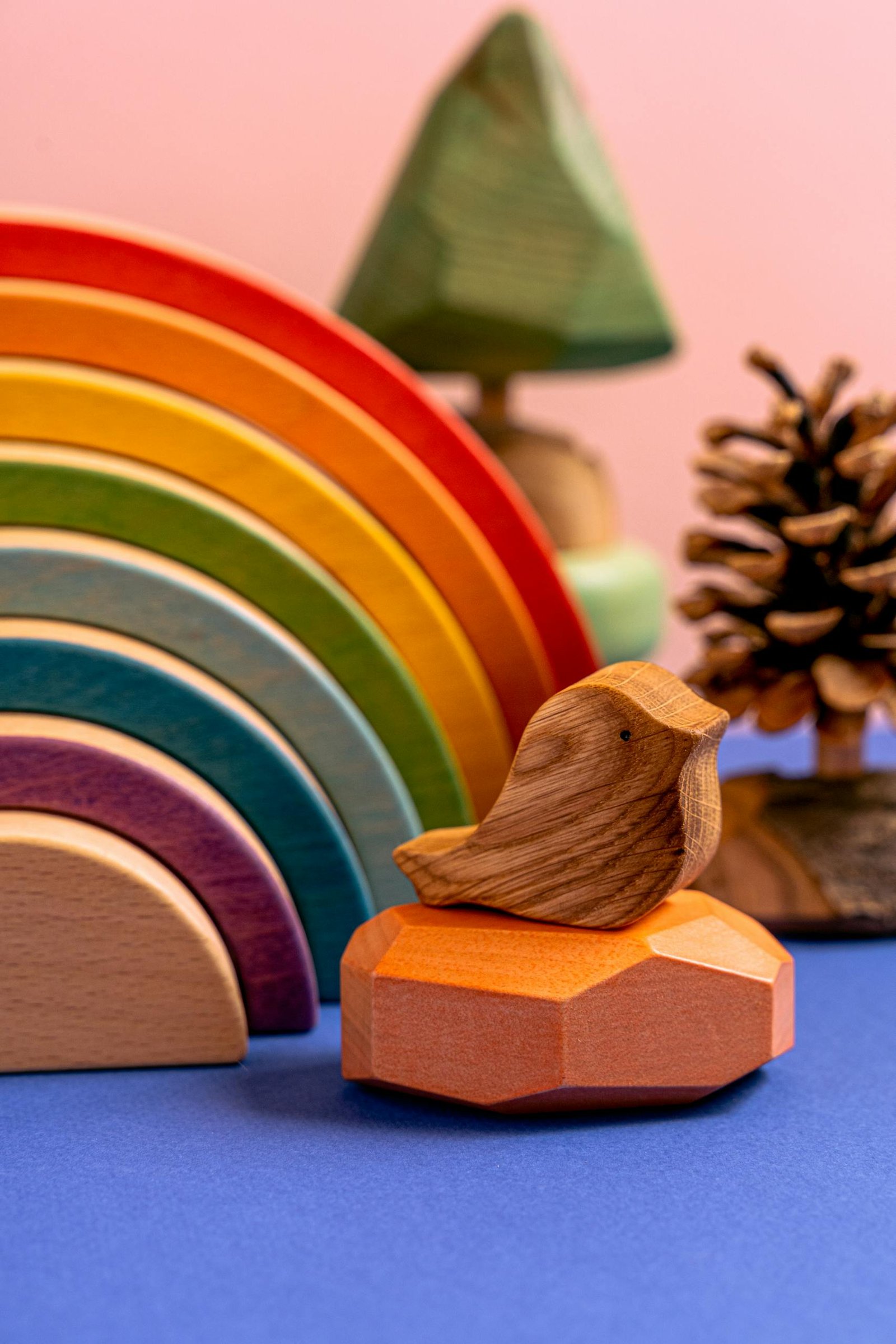 A vibrant wooden bird and rainbow in a studio setup with playful colors.